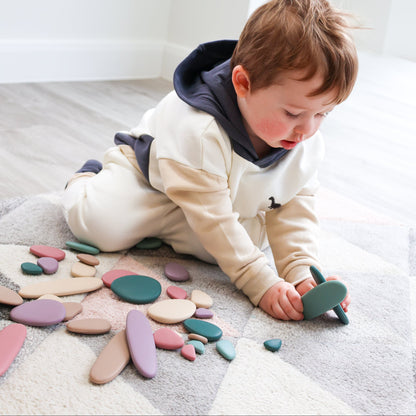 Colorful silicone stacking pebbles by baby ellor, arranged in a pyramid, showing smooth, rounded textures for developmental play.