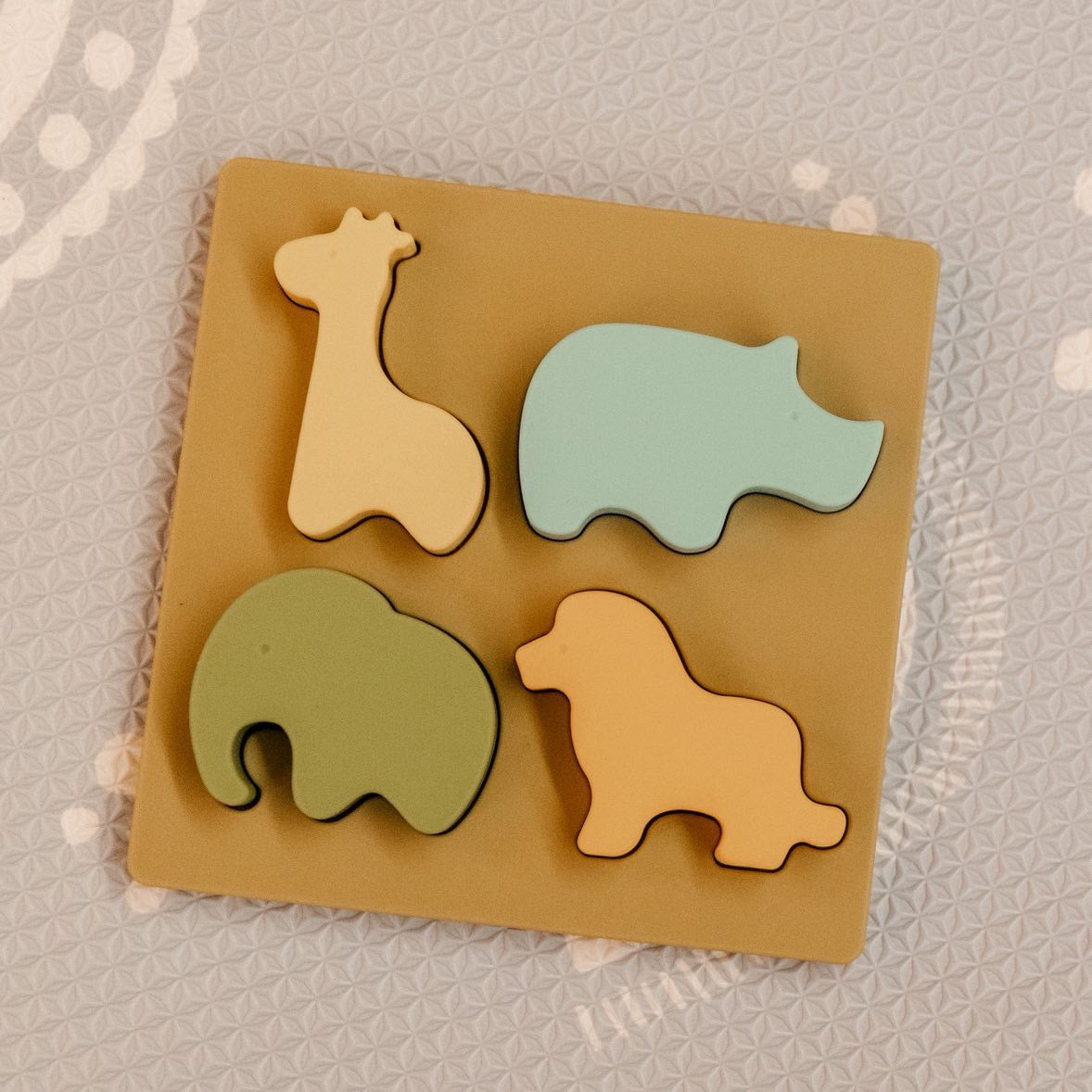 Set of colorful animal-shaped silicone toys on a beige base with a patterned background.