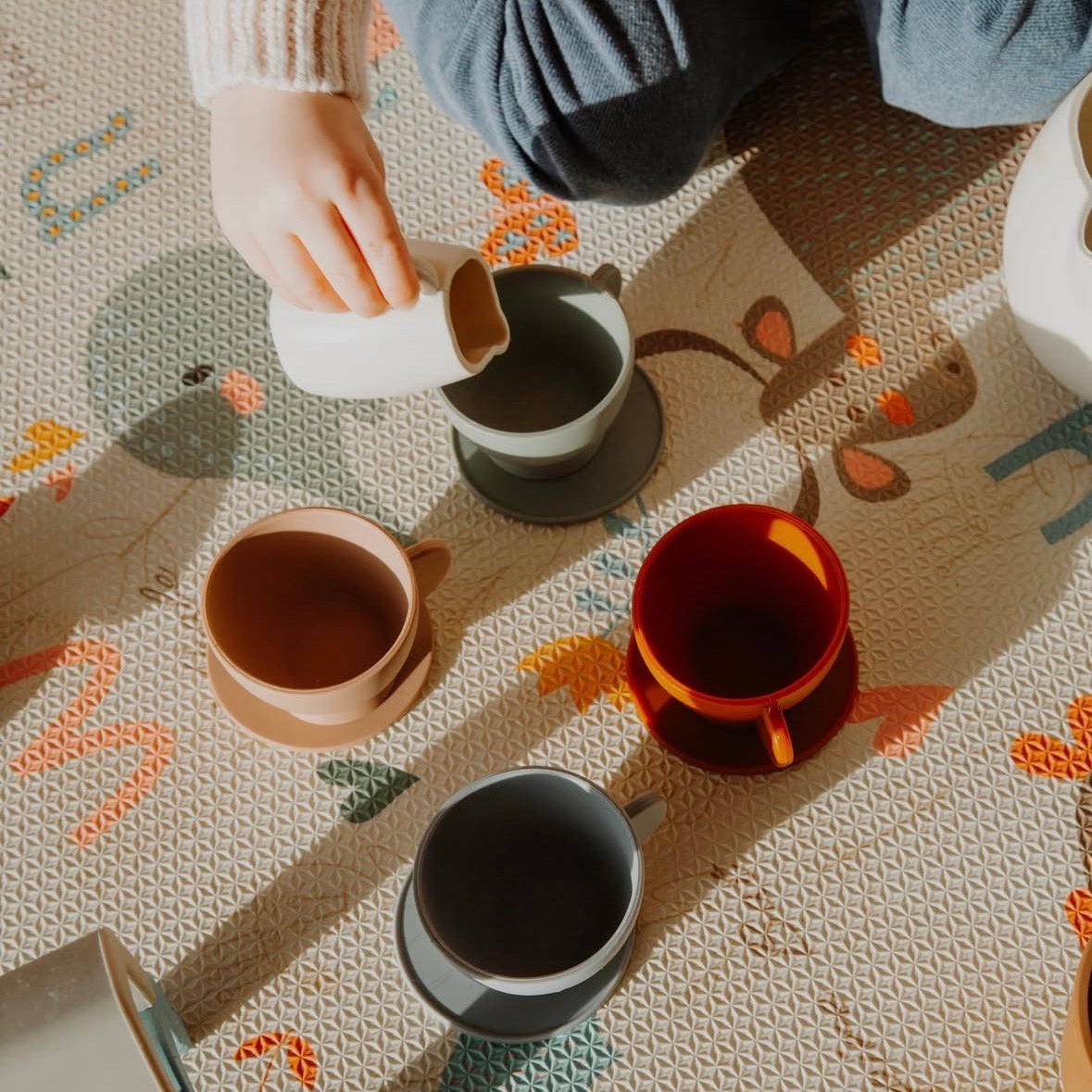 child on play mat playing with silicone tea set
