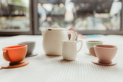 Baby Ellor silicone tea set with cups, teapot, and utensils on a wooden surface, ideal for children's pretend play.