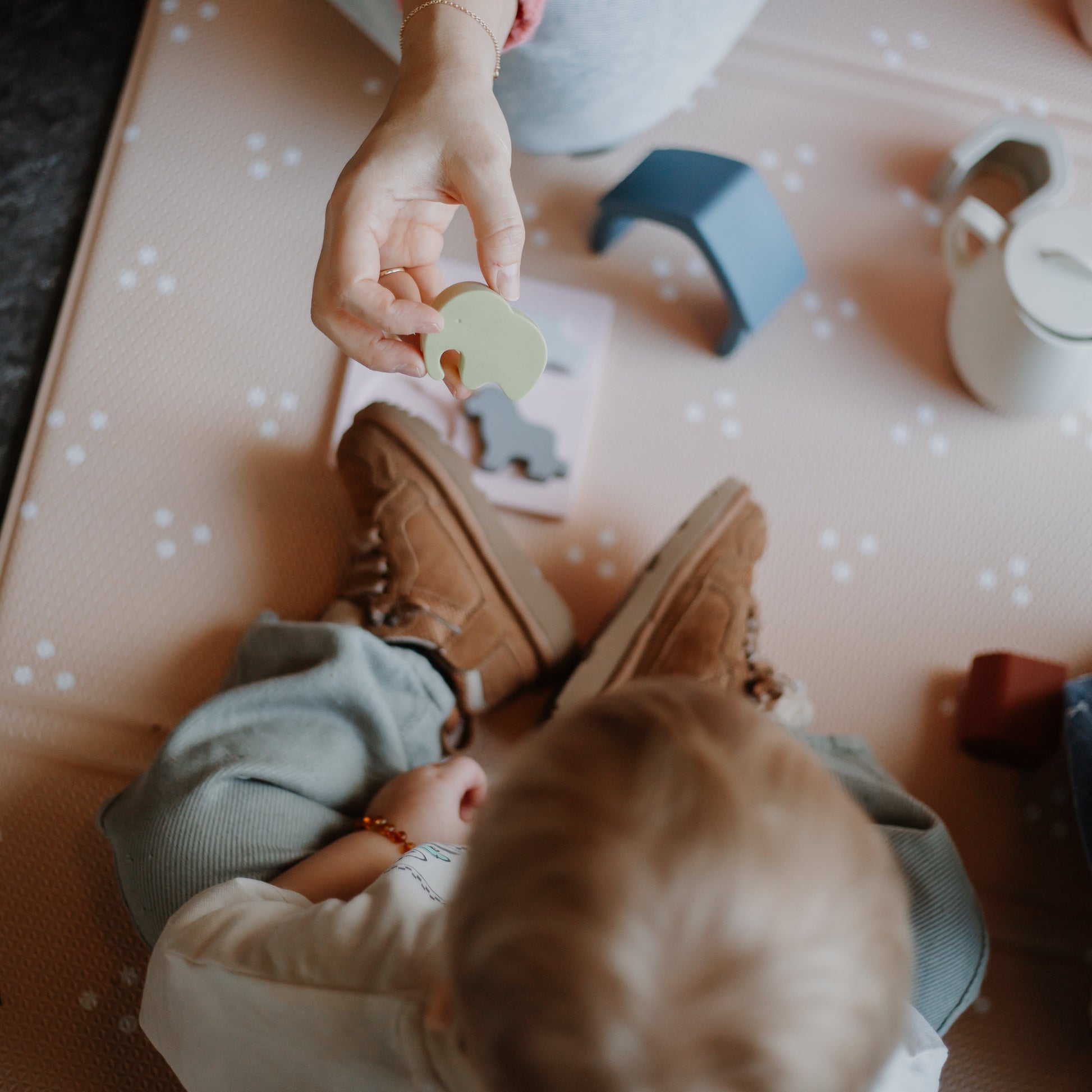 Child playing with silicone animal shape toys on a soft play mat
