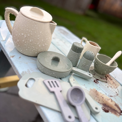 Set of Silicone  kitchen toys  including a teapot, cups, and tools on a rustic surface.